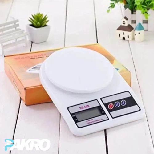 Digital kitchen scale on a wooden surface with a box and decorative items in the background