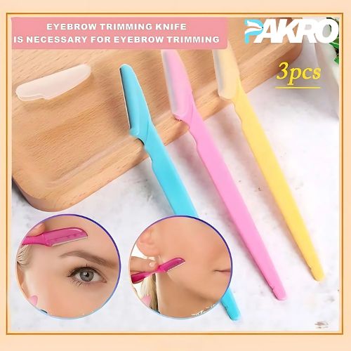 Set of three eyebrow trimming knives in blue, pink, and yellow with a wooden stand on a white background.