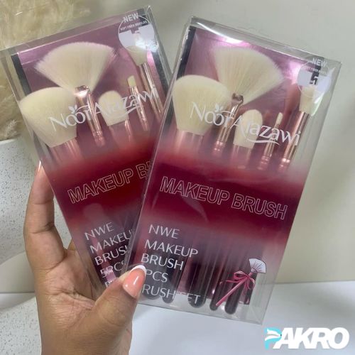 Two packages of Noozazzam makeup brushes held by a hand on a light background.