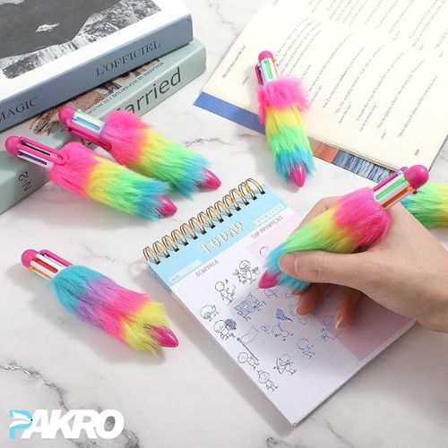 Colorful fluffy pens with a hand holding one, on a notebook and books background.