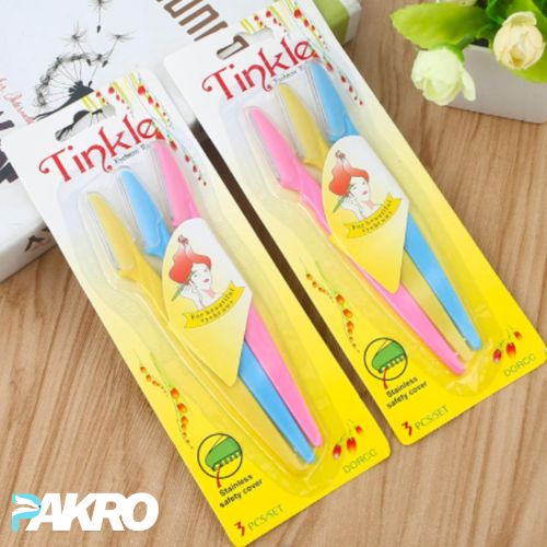 Two packages of Tinkle toothbrushes with colorful handles on a wooden surface.
