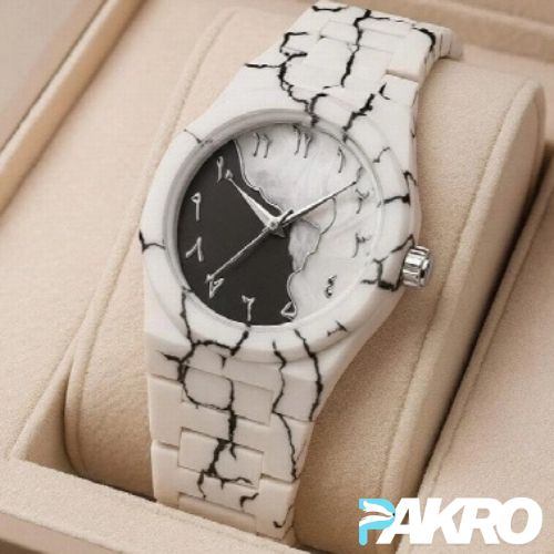 Marble-patterned watch on a beige cushion with 'PAKRO' branding.
