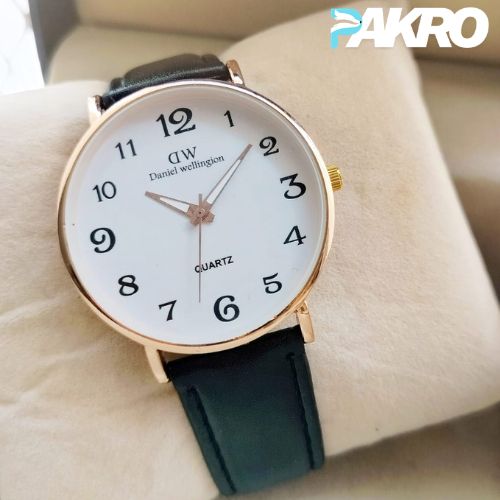 Daniel Wellington watch with black strap on a beige surface, brand 'PAKRO' visible.