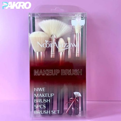 Packaged makeup brush set with Noot Alazawi branding on a pink background