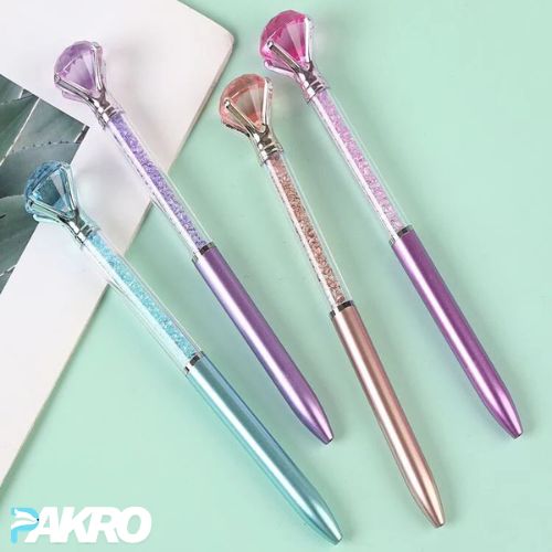 Colorful pens with gemstone designs on a light green background, featuring the brand 'PAKRO'.