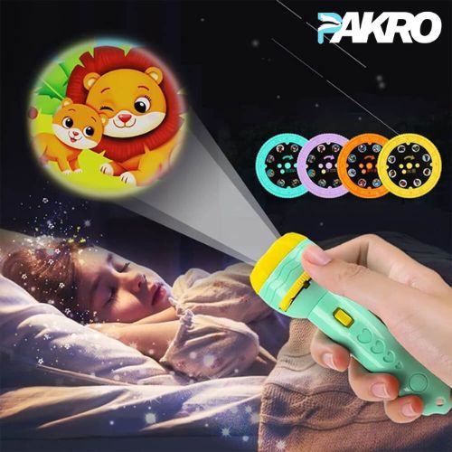 Toy projector with lion-themed lamp head held by a child, projected onto a sleeping child's face, with 'PAKRO' branding.