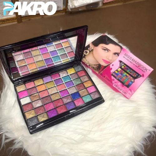 Makeup palette with colorful shades on a white fur surface, next to a product box featuring a woman's face.