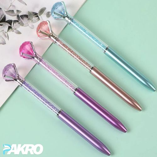 Four decorative pens with gem-like tips on a light green background, featuring the brand 'PAKRO'.